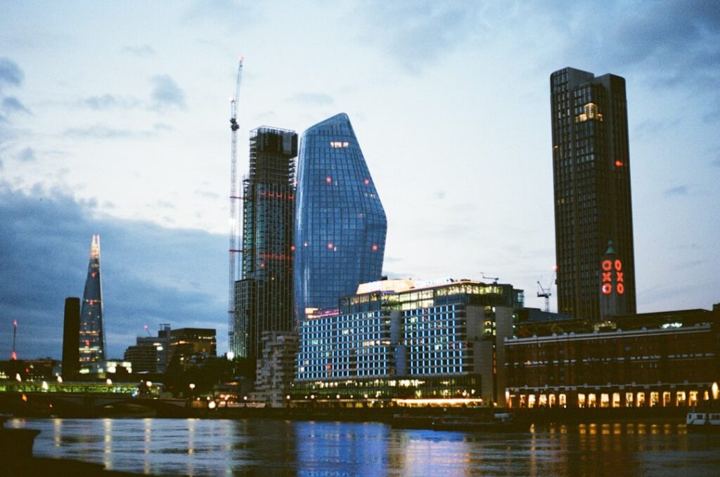 Skyscrapers line a river during a twilight hour.